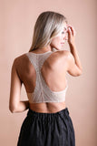 Seamless lace beige bralette with racerback design for layering outfits.